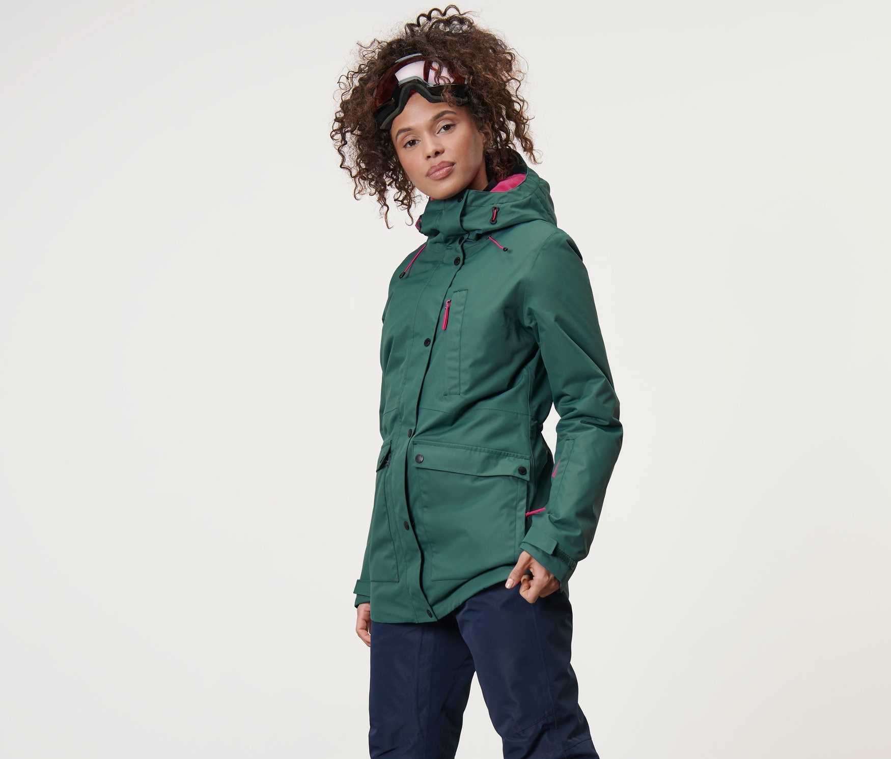 Žena má na sobě lyžařskou a snowboardovou bundu a lyžařské kalhoty.