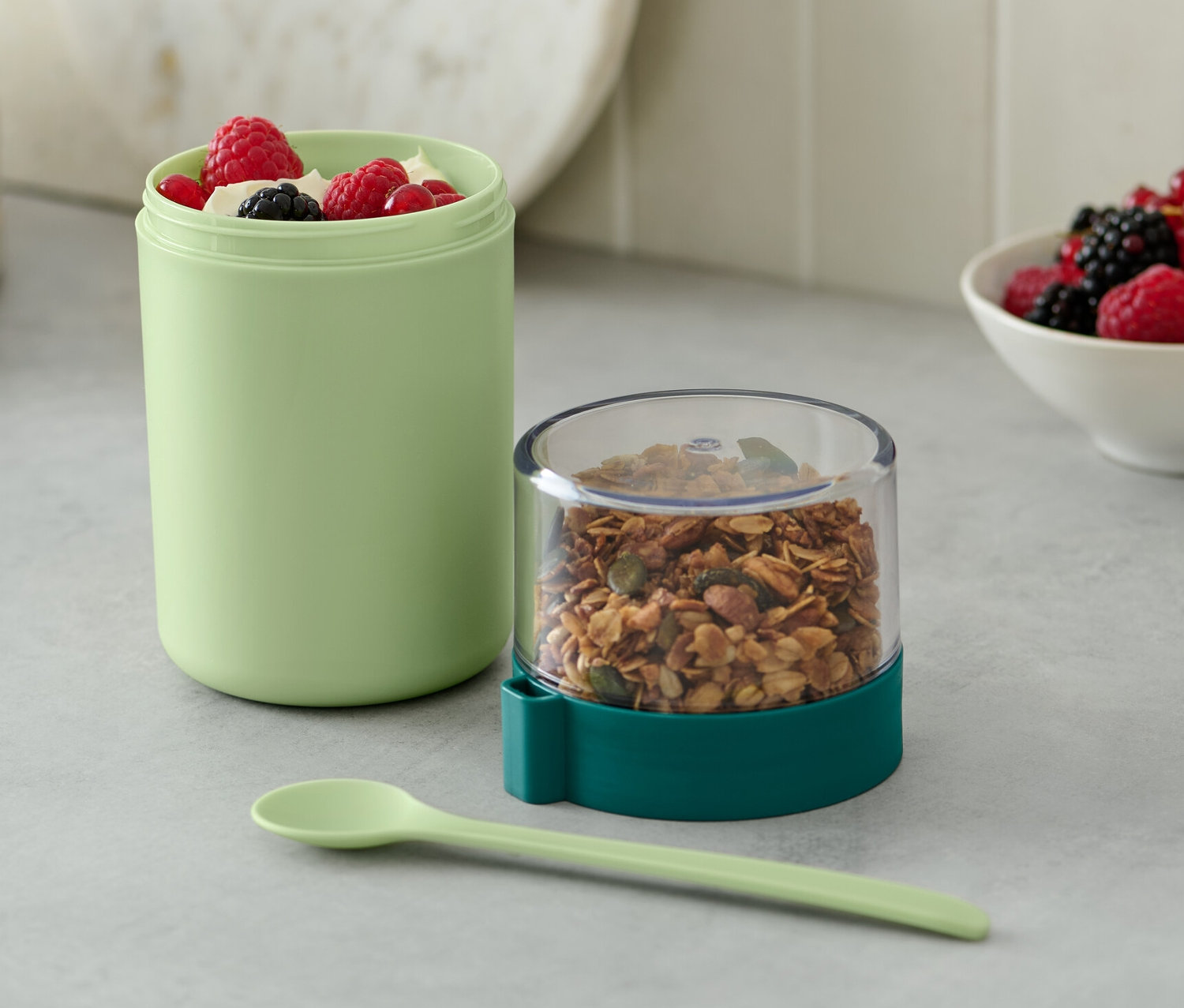 Zelený kelímek na jogurt na cesty s müsli a bobulemi.