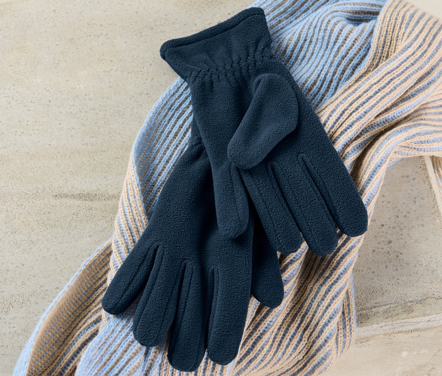 Na svetru leží pár fleecových rukavic.