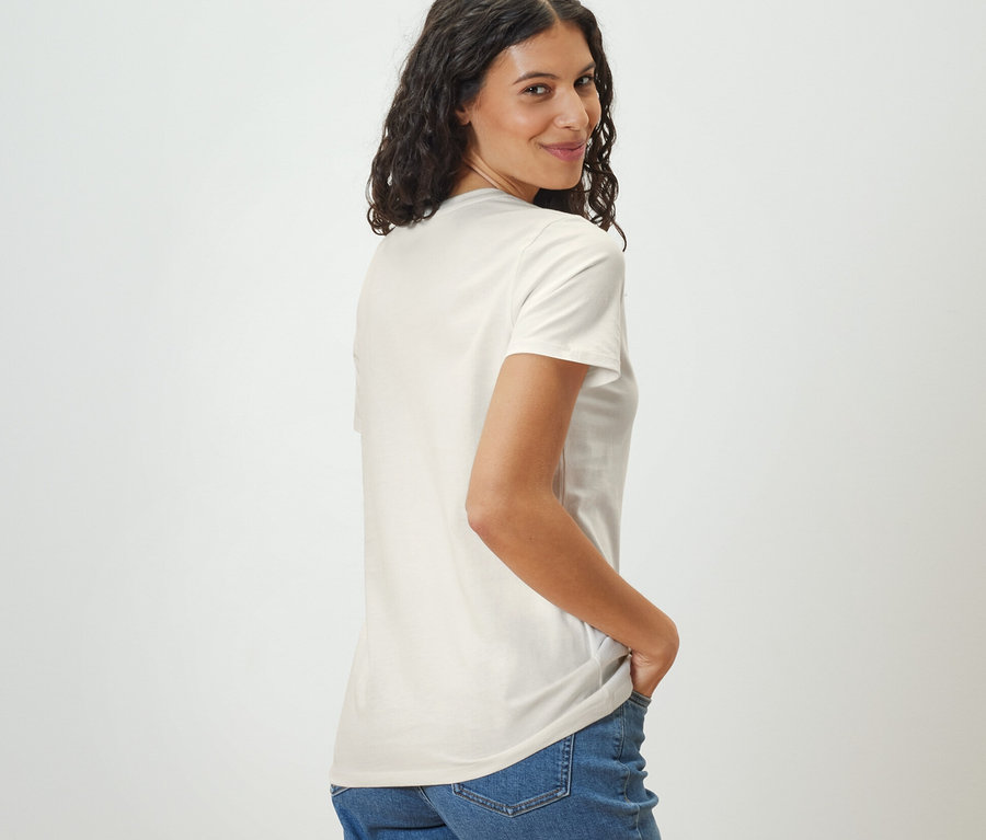 Žena se dívá přes rameno a má na sobě bílé tričko Basic.
