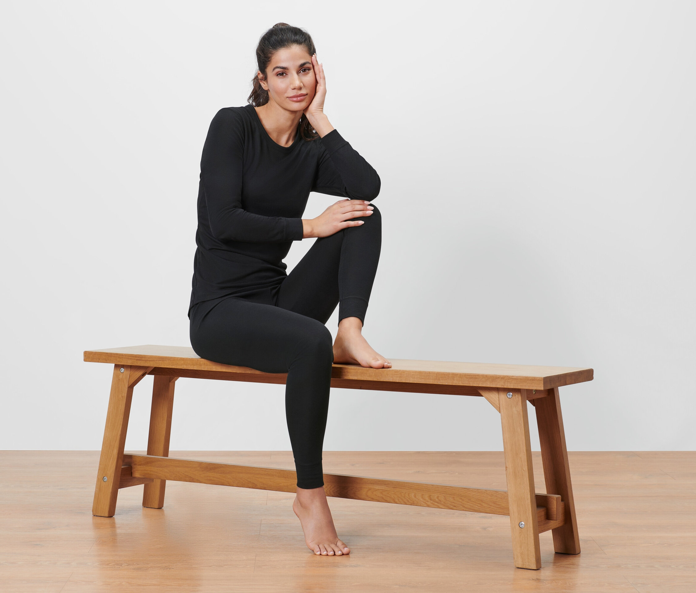 Žena sedí na lavici v černém funkčním termoprádle.