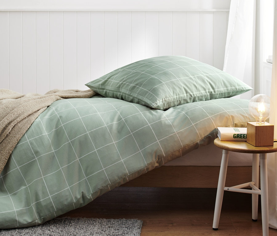 Zelené bavlněné povlečení standardní velikosti s bílým mřížkovaným vzorem na posteli.