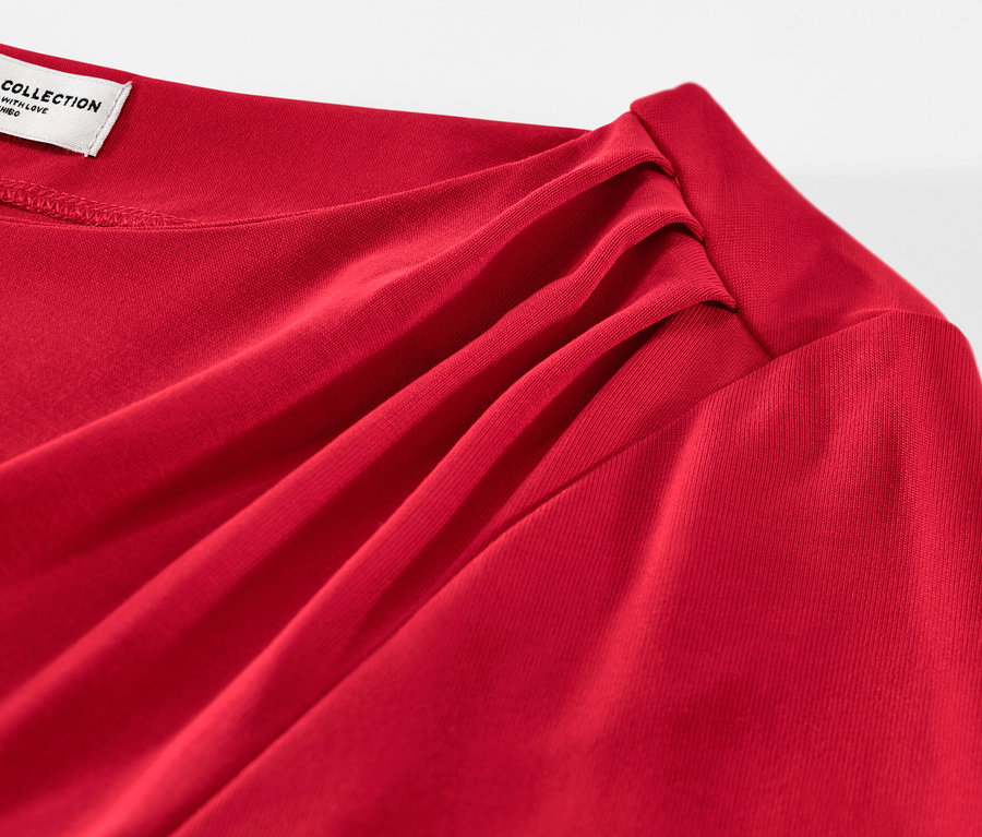 Detail červeného halenkového trika s řasením.