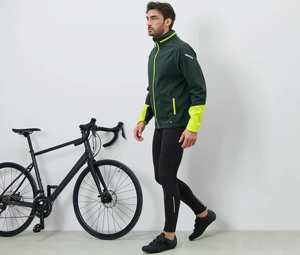 Muž kráčí vedle černého kola a má na sobě cyklistické kalhoty.