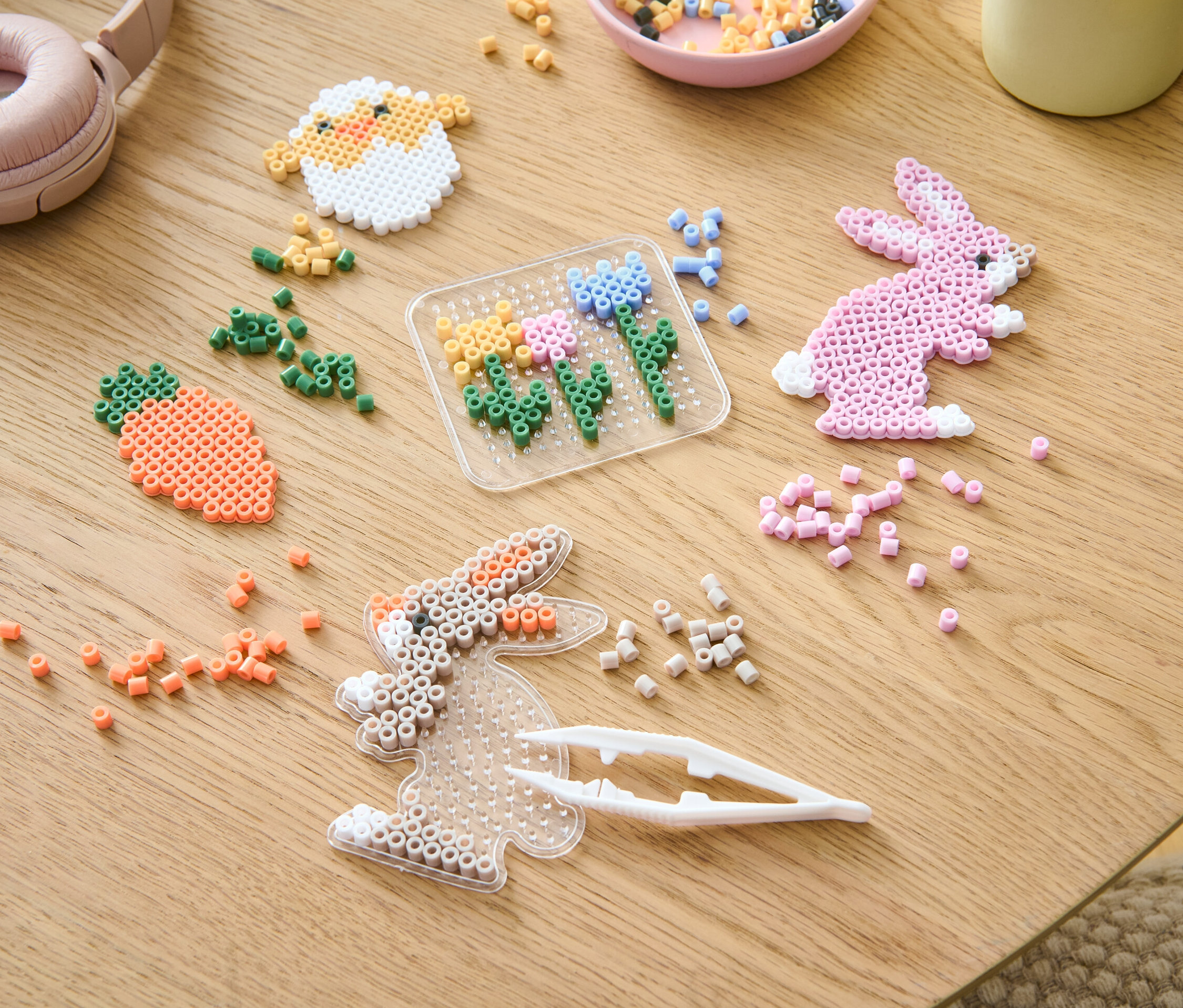 Na stole leží kreativní sada zažehlovacích korálků a korálky různých barev.