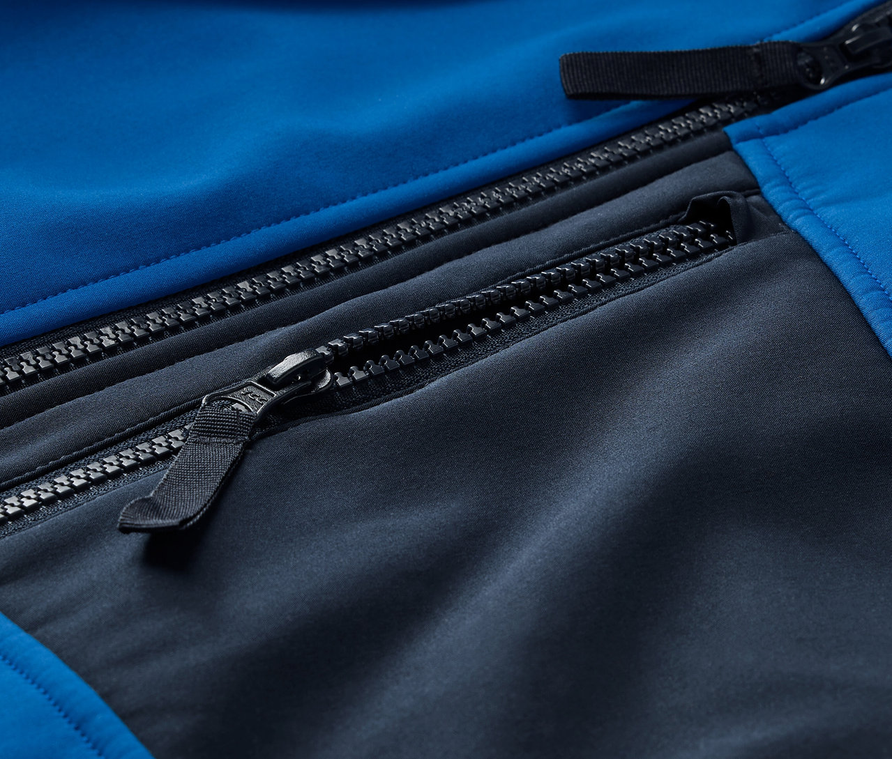 Detail modro-černé softshellové bundy se zipy.