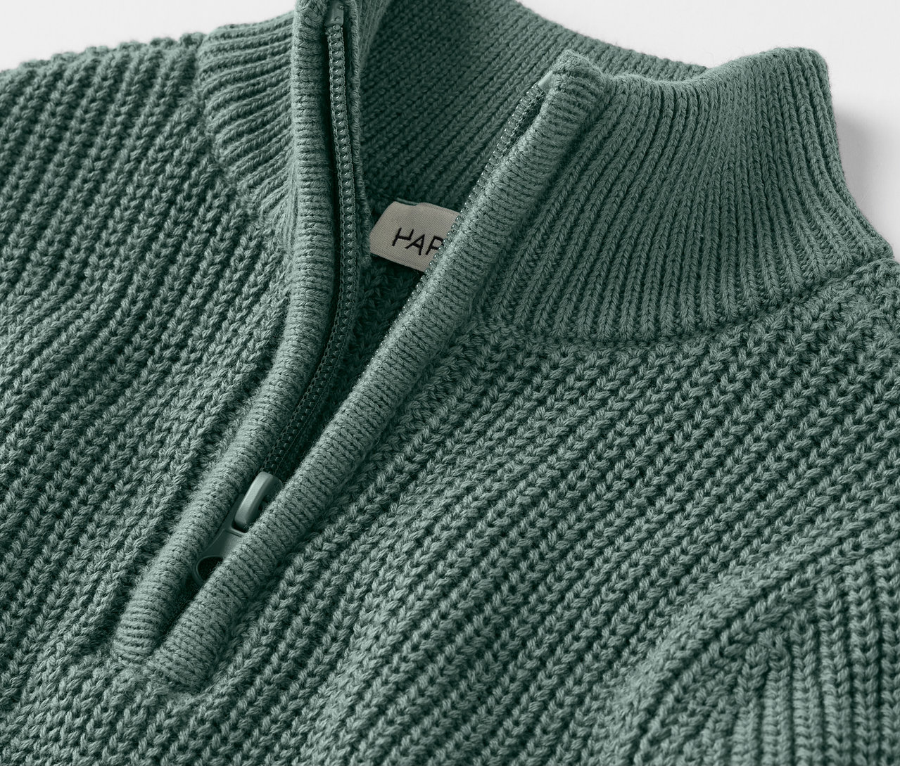 Detailní záběr na dětský pletený svetr troyer s krátkým zipem.