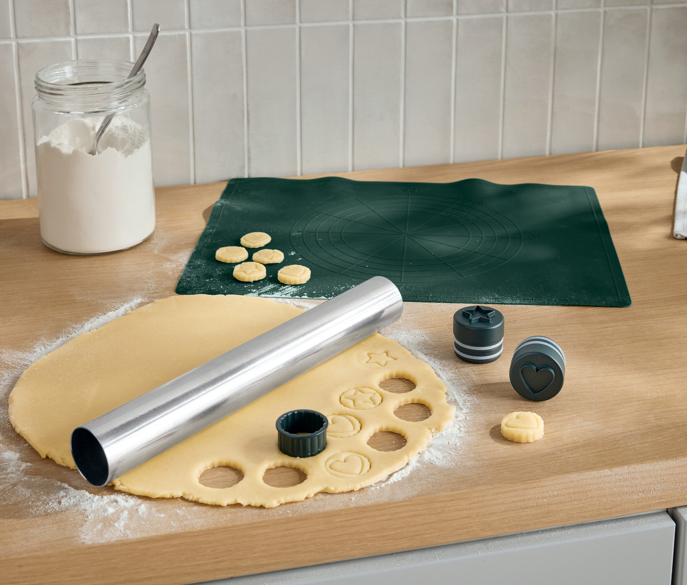 Vykrajování sušenek na dřevěné desce válečkem a vykrajovátky různých tvarů.