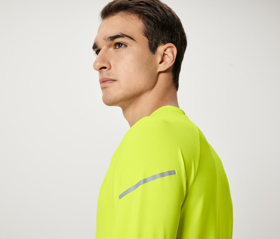 Muž s hnědými vlasy a neonově žlutým tričkem se dívá doleva.