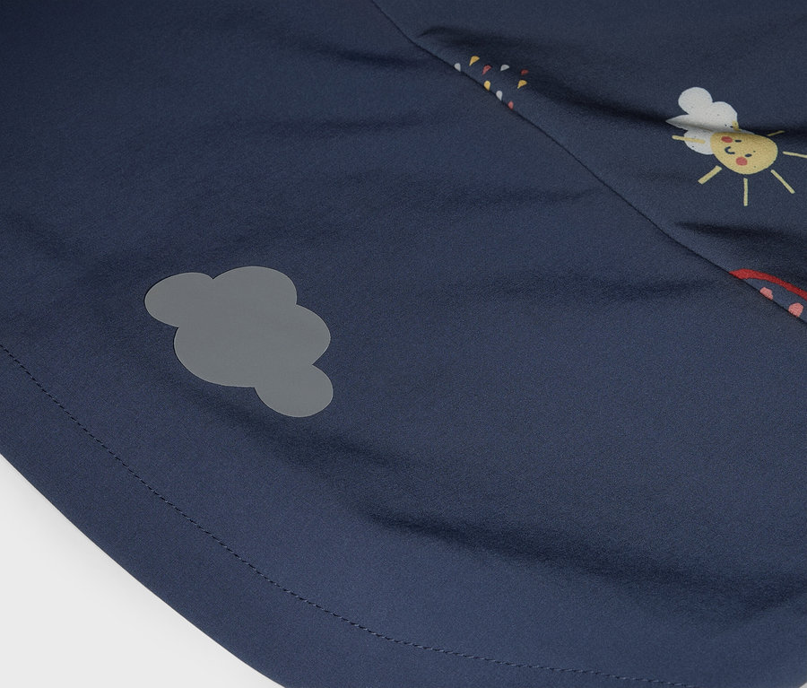 Detailní záběr tmavě modré látky se šedou nášivkou ve tvaru mraku a potiskem obličeje slunce.