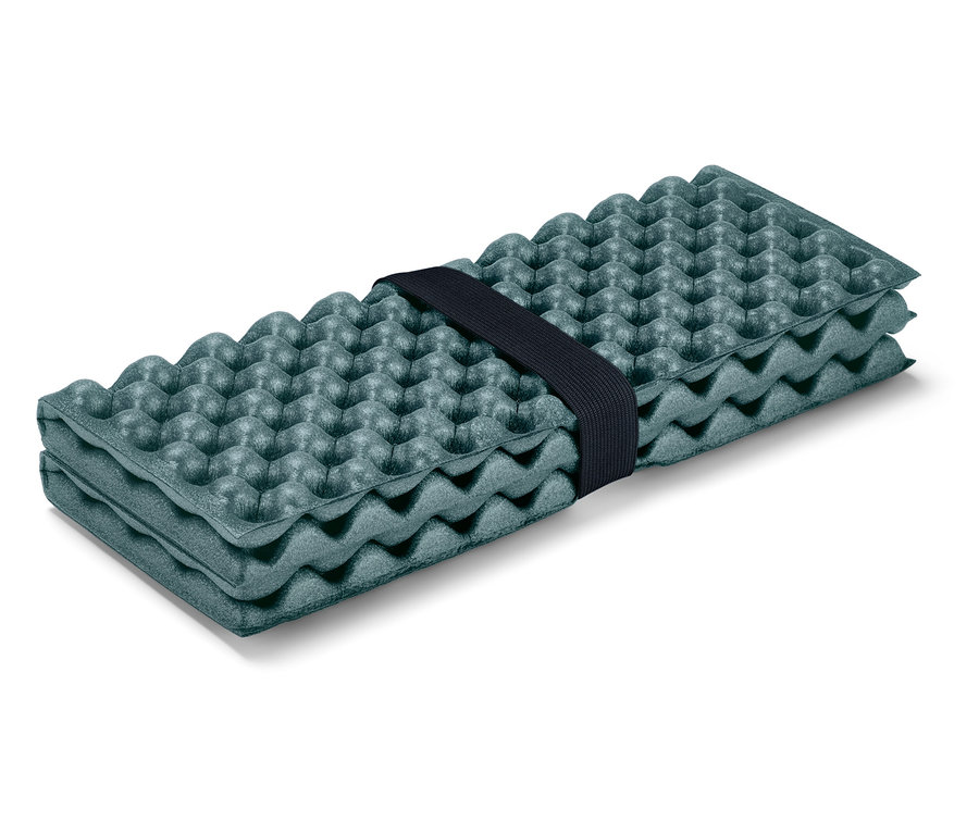 Složená olivově zelená karimatka s výstupky, držená černou gumičkou.