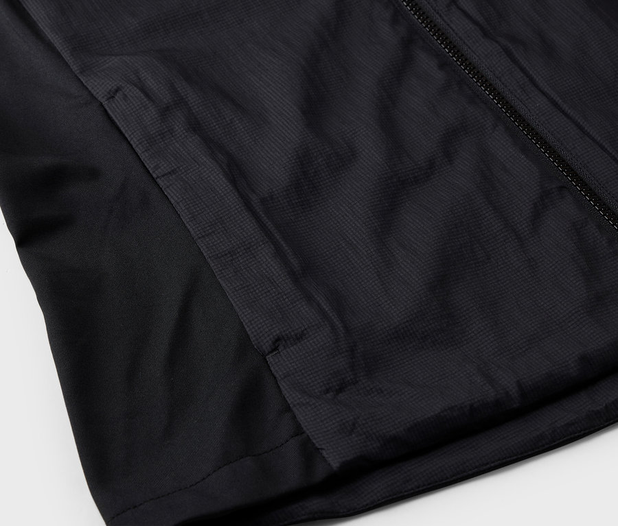 Detailní pohled na černou bundu se zipem a boční kapsou.