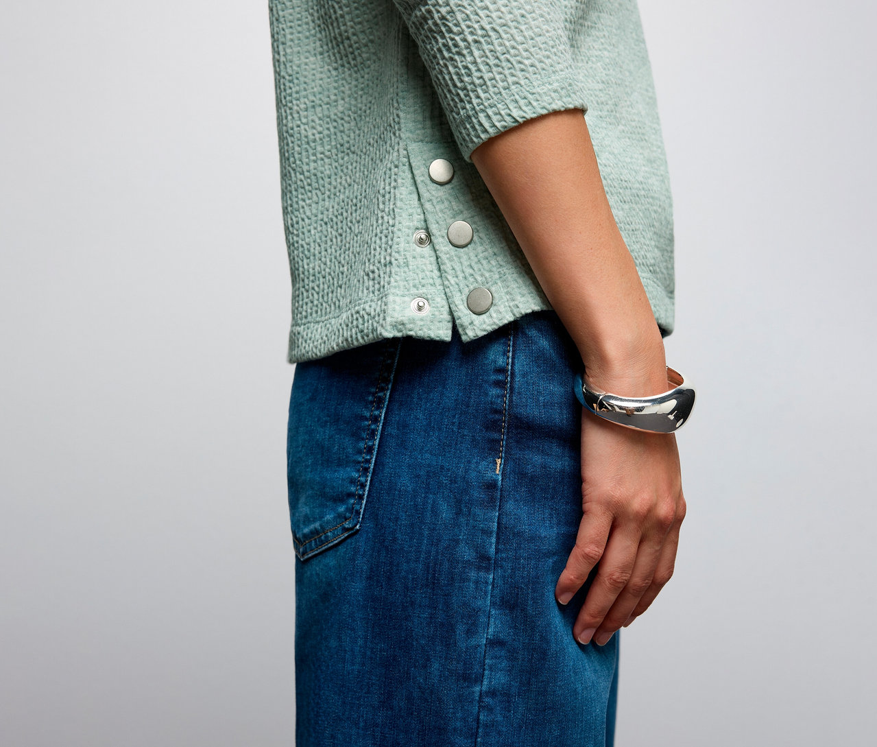 Detailní záběr na ženu, která má na sobě strukturované tričko Street One a džínovou sukni.