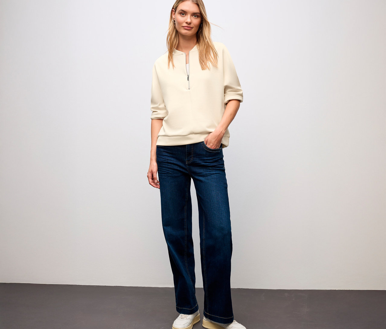 Blondýna stojí a má na sobě triko ze směsi modalu Street One, džíny a tenisky.