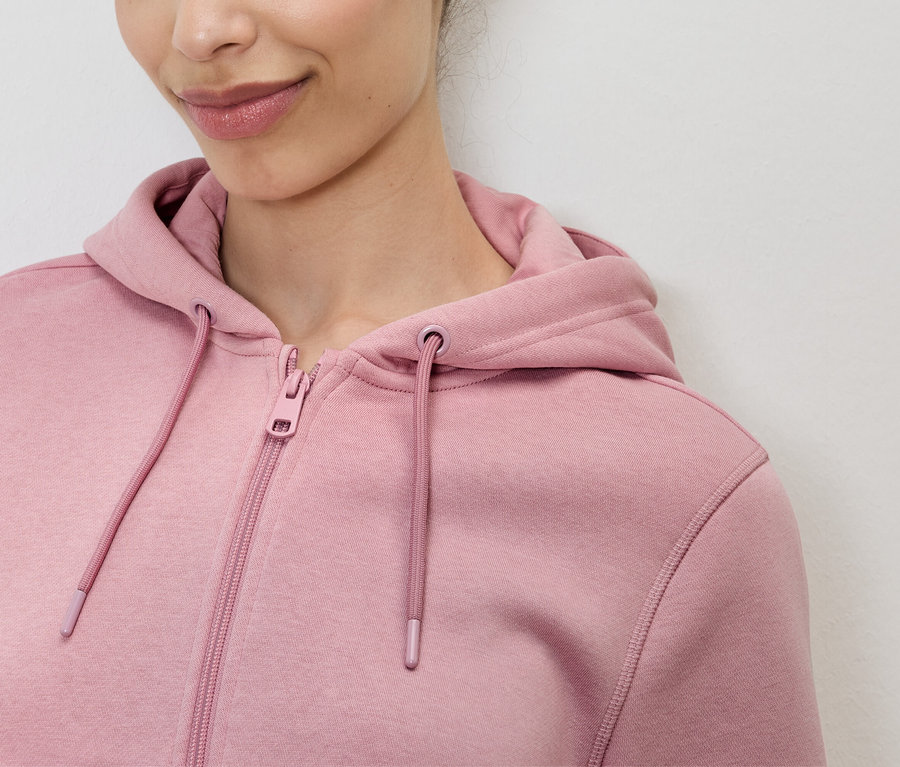 Detailní záběr ženy v růžové mikině s kapucí na zip.