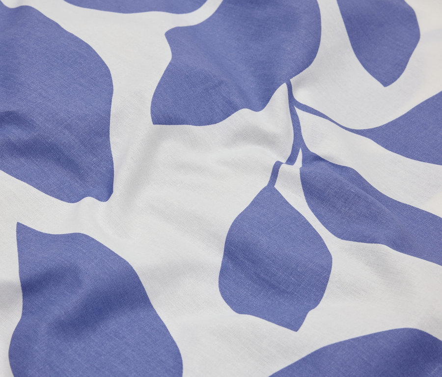 Detail látky s modrým vzorem listů na bílém pozadí.