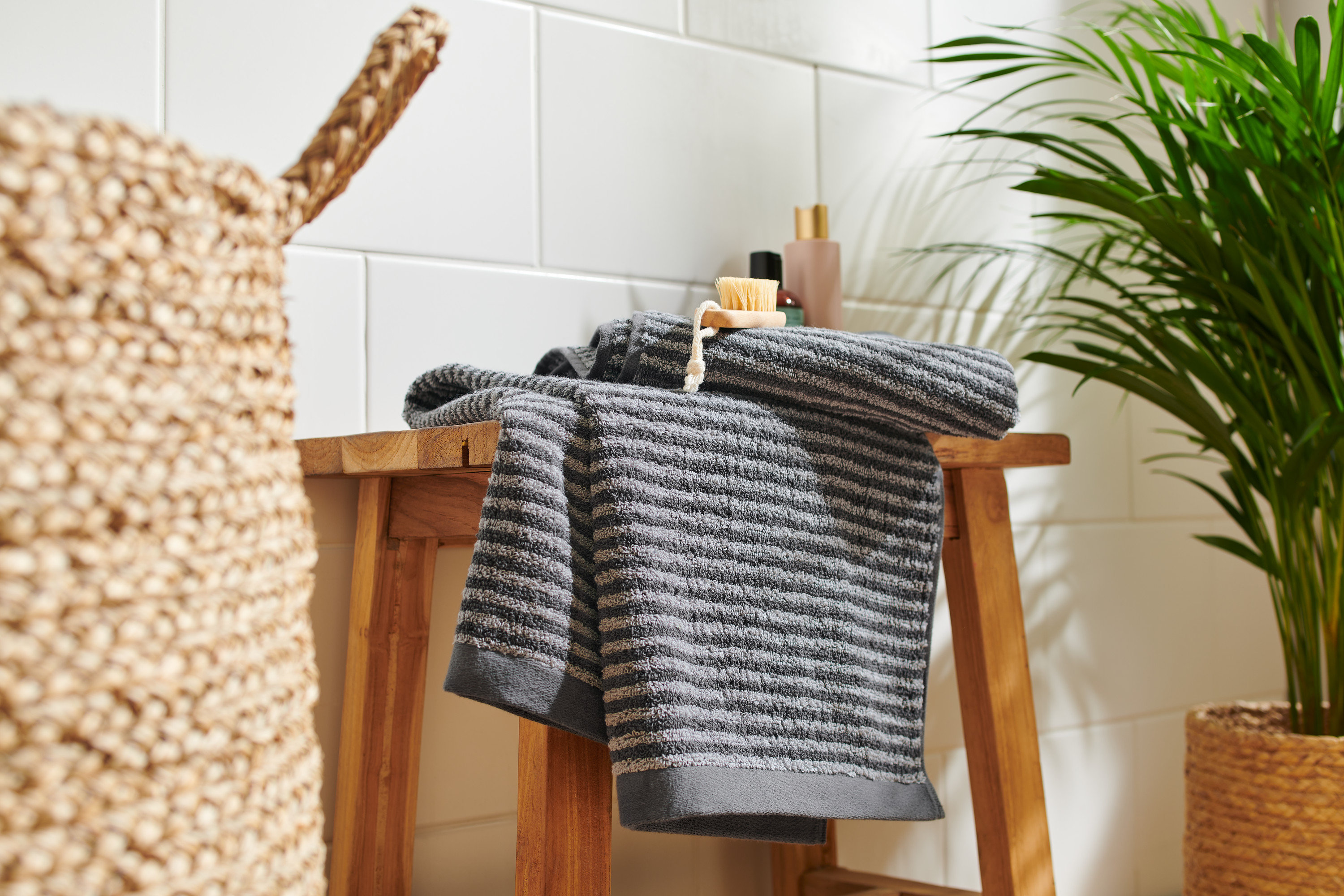 Na dřevěné stoličce leží dva vysoce kvalitní antracitové ručníky.