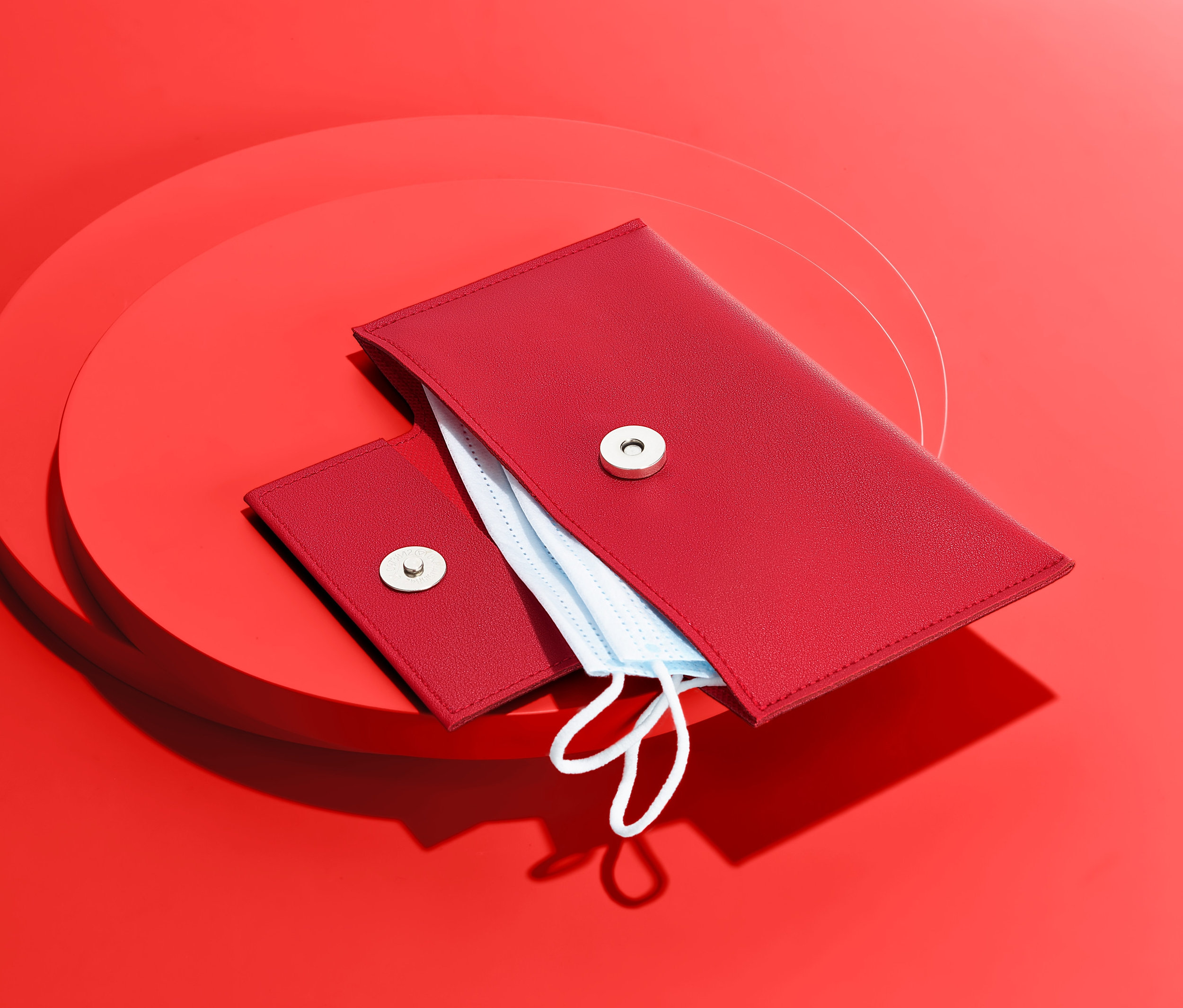 Červené pouzdro na ochranné roušky na červeném pozadí.