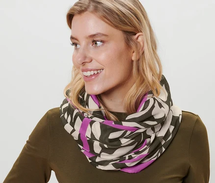 Žena s blond vlasy nosí kruhovou šálu s potiskem.