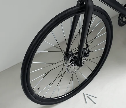 Detailní záběr na černé jízdní kolo s 36 reflexními prvky na paprscích kola.