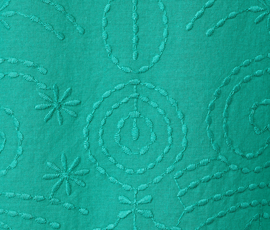 Detail zelené halenky s výšivkou.