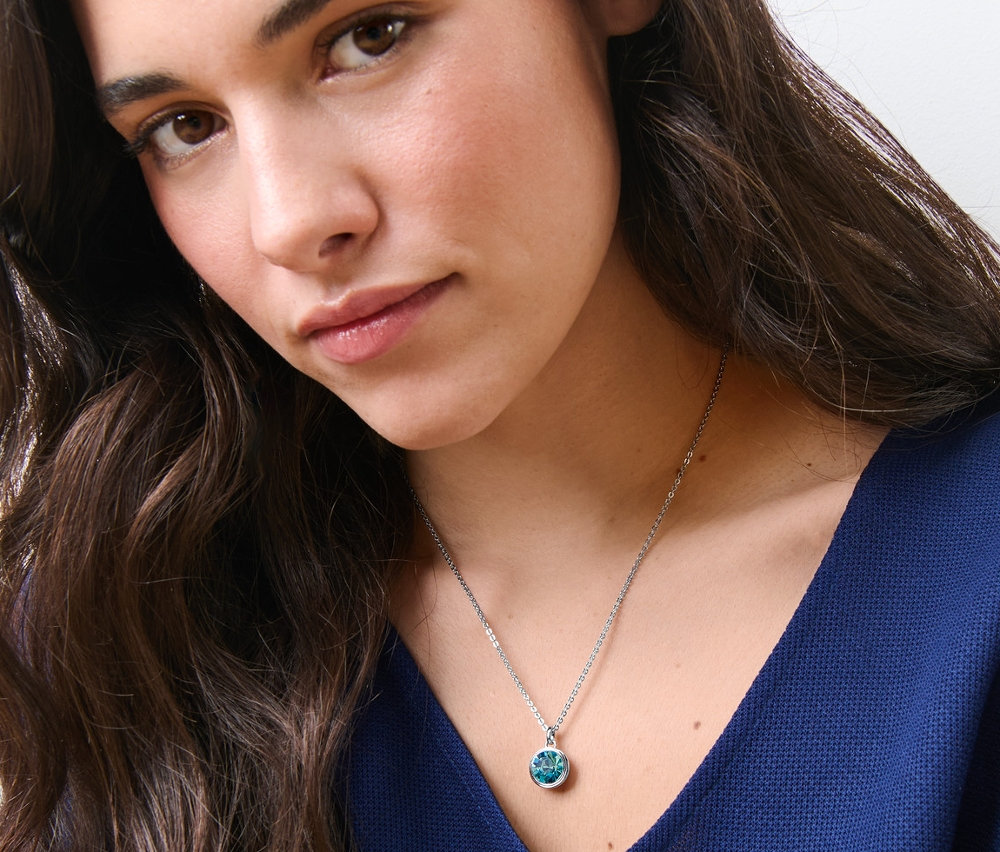 Žena má na sobě řetízek s přívěskem Blue Shades.