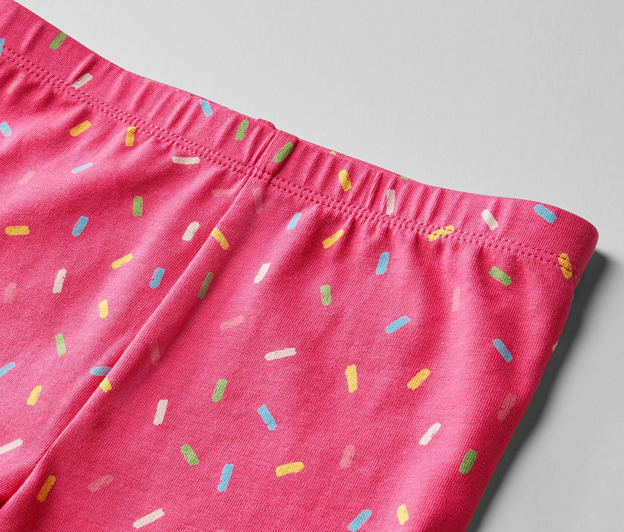 Detail horní části růžových legín s potiskem barevných posypek. Dětské cyklistické legíny, 2 ks, růžová a žlutá.