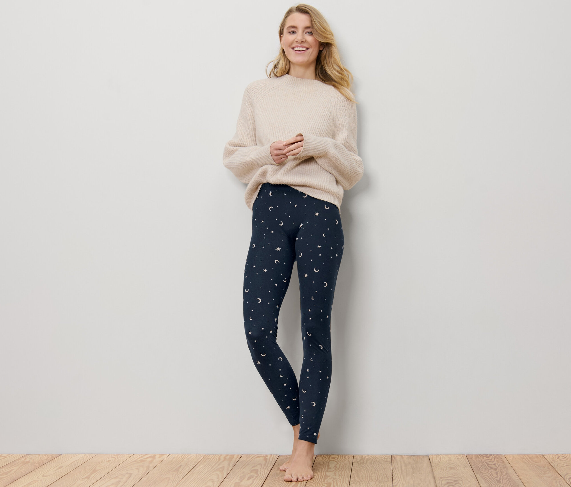 Žena stojí a má na sobě hebké legíny s potiskem.