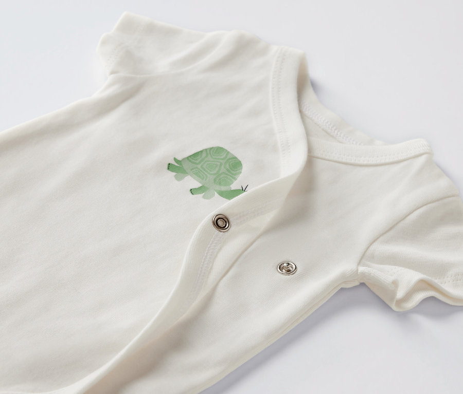 Detail bílého body s krátkým rukávem a obrázkem želvy.