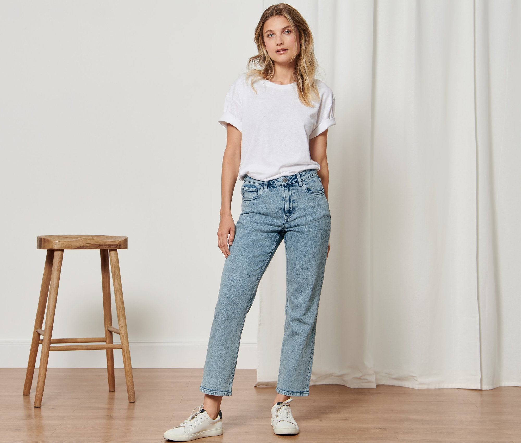 Žena pózuje na kameru a má na sobě džíny »Fit Ava«.