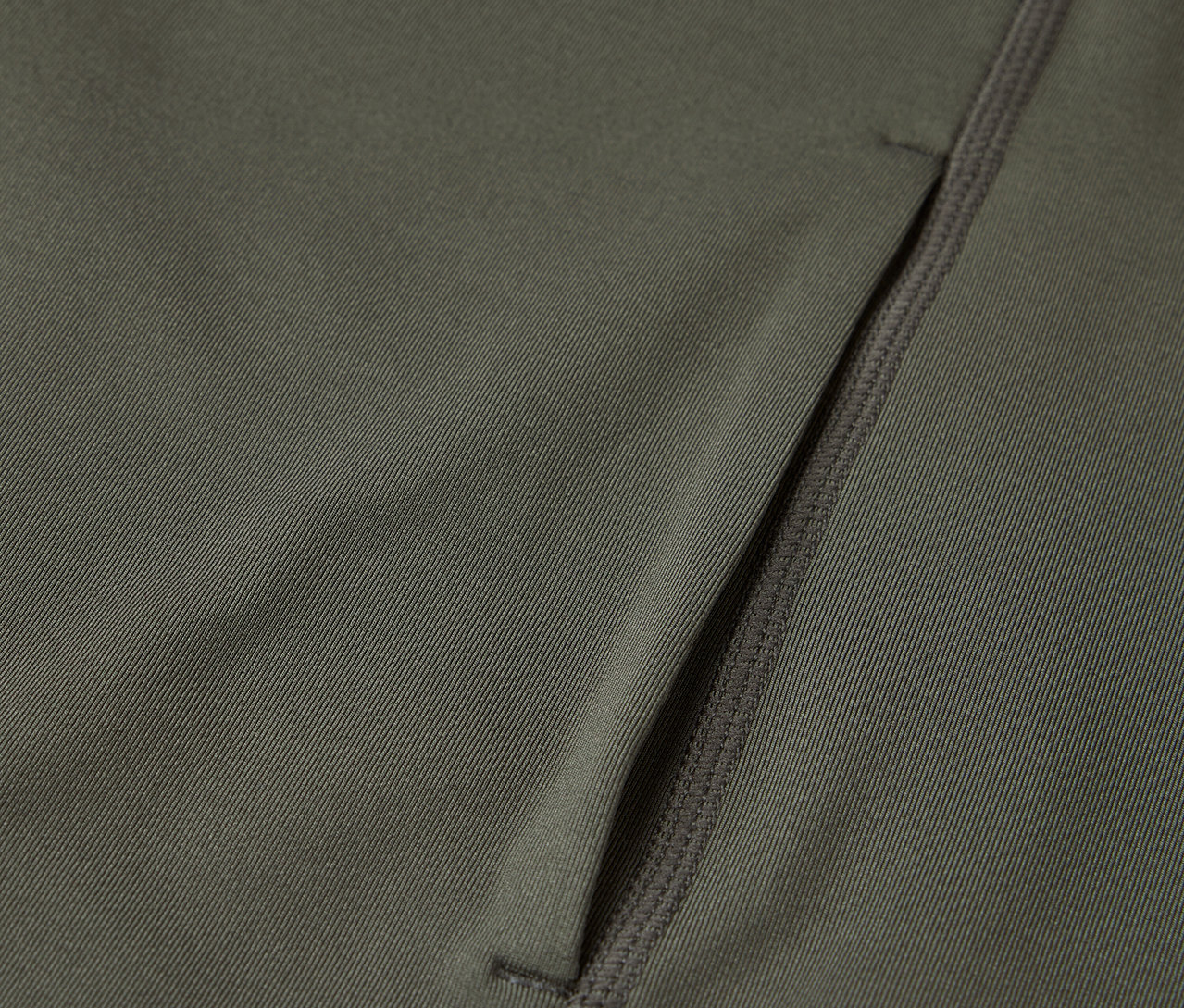 Detailní záběr olivově zelené látky s kapsou na zip.