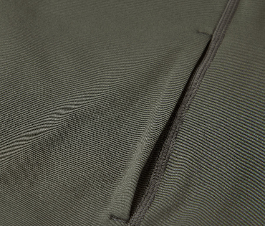 Detailní záběr olivově zelené látky s kapsou na zip.