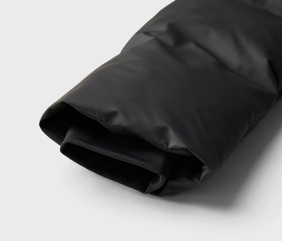 Detailní záběr na rukáv černé péřové bundy.