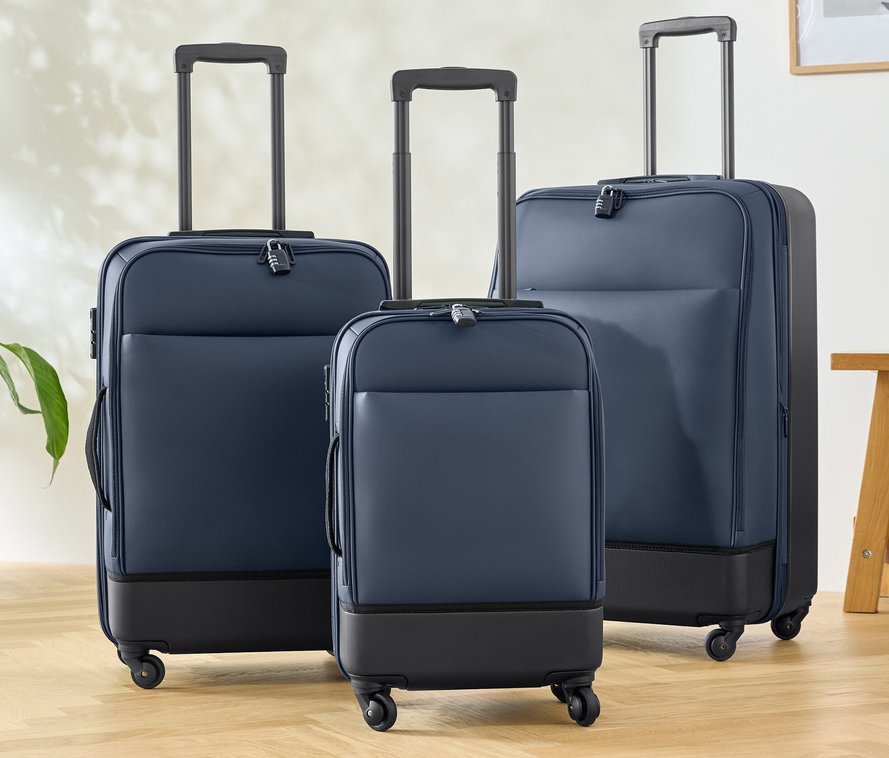 Tři hybridní kufry (malý, střední a velký) stojí na dřevěné podlaze.