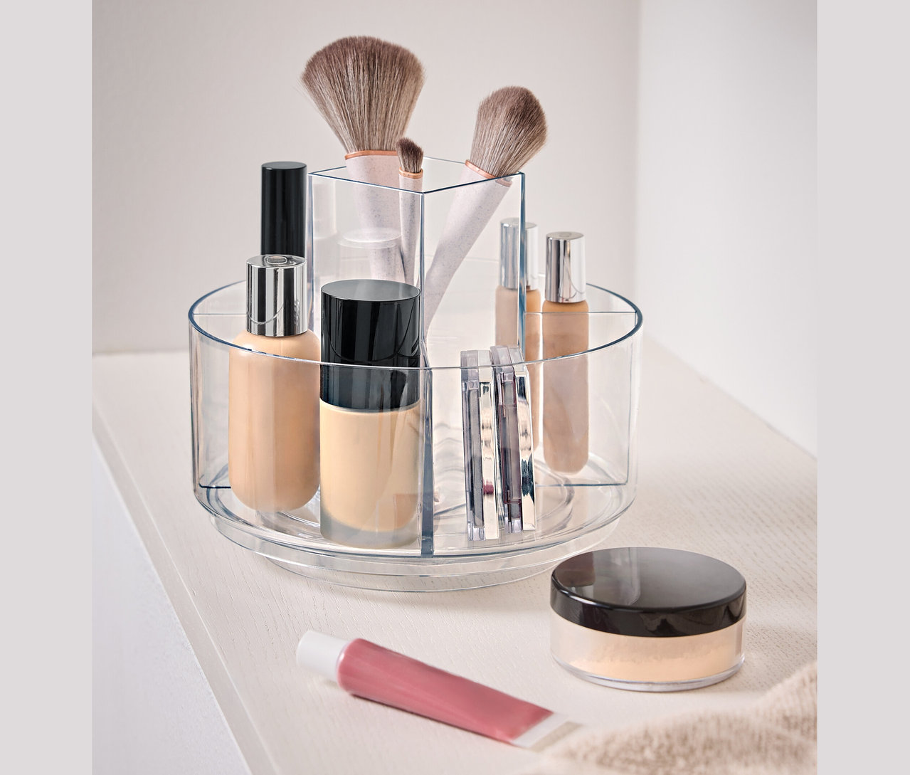 Čirá otočná nádoba s kosmetikou na bílém povrchu.