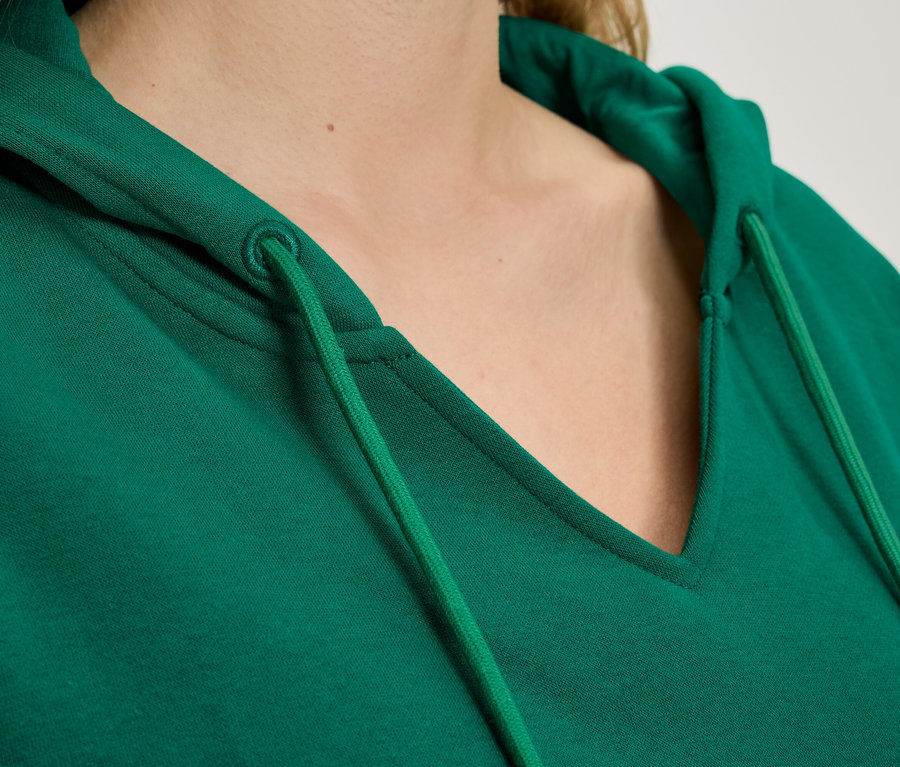 Detail zelené mikiny s kapucí a šňůrkami.