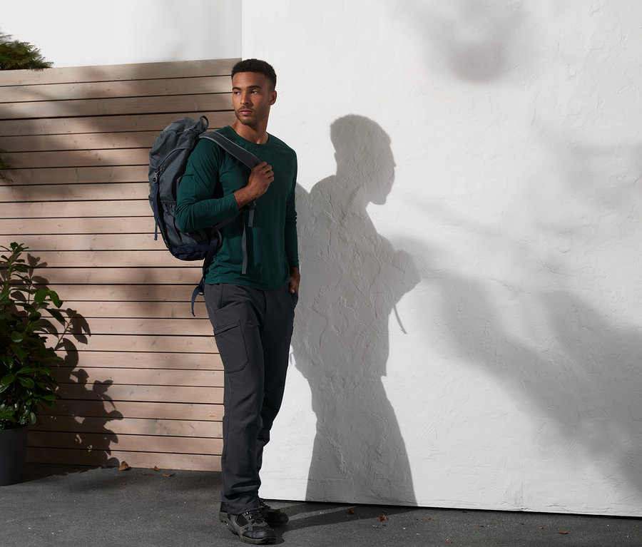 Muž s batohem stojí venku a má na sobě termokalhoty.