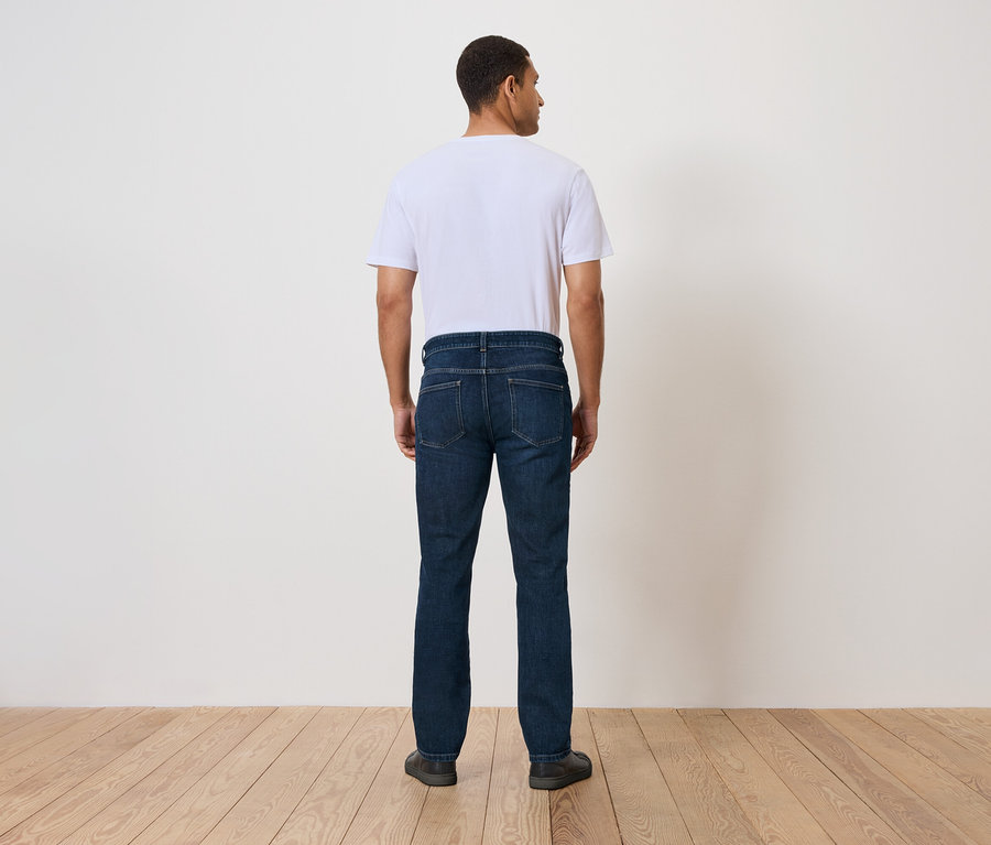 Muž stojí zády k fotoaparátu a má na sobě džíny a tričko.