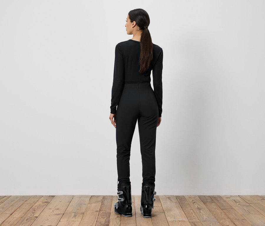 Žena v černém lyžařském oblečení stojí zády.