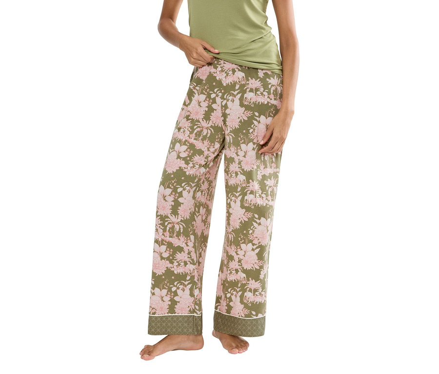 Žena má na sobě zelený tílko a olivově zelené pyžamové kalhoty s růžovým květinovým vzorem.