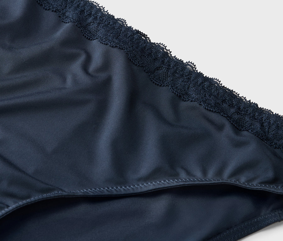 Detailní záběr na tmavě modré dámské kalhotky s krajkovým lemem.