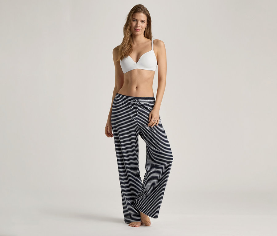 Žena má na sobě bílou podprsenku s měkkými košíčky a modro-bílé pruhované kalhoty.