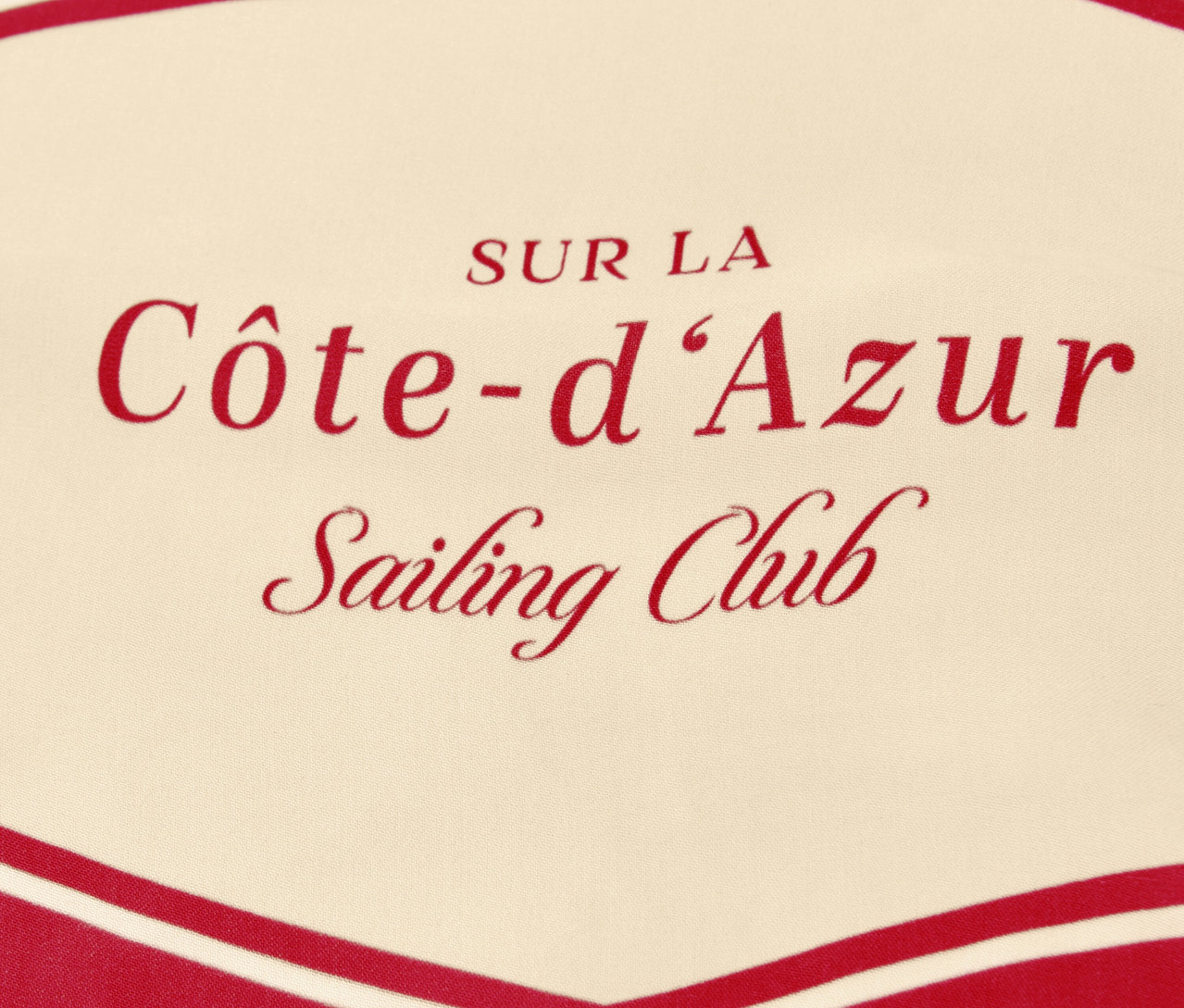 Detail šátku na krk Street One »Nicki« s červeným nápisem „Côte-d'Azur Sailing Club“ na béžovém pozadí.