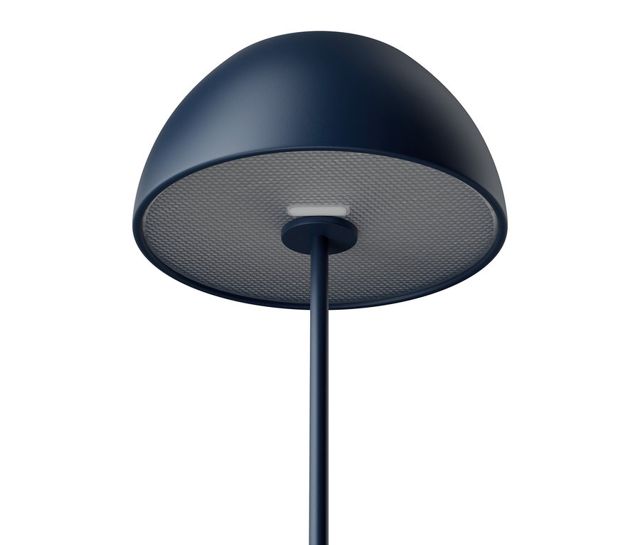Detailní záběr na modrou stojací lampu se šedým, perforovaným stínidlem na bílém pozadí.