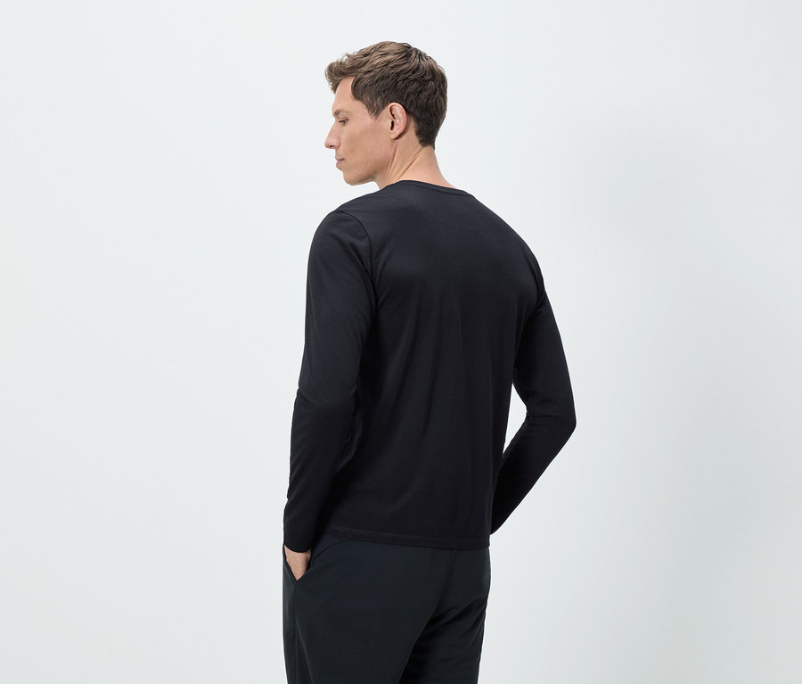 Muž zezadu v černém tričku s dlouhým rukávem a kalhotách.