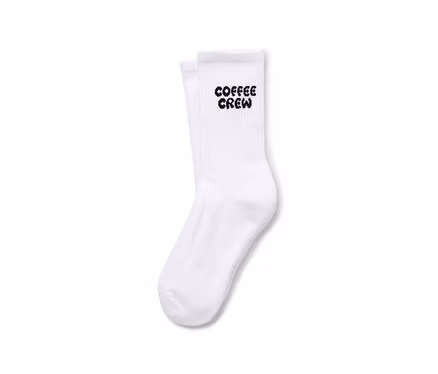 Pár bílých ponožek s nápisem "Coffee Crew".