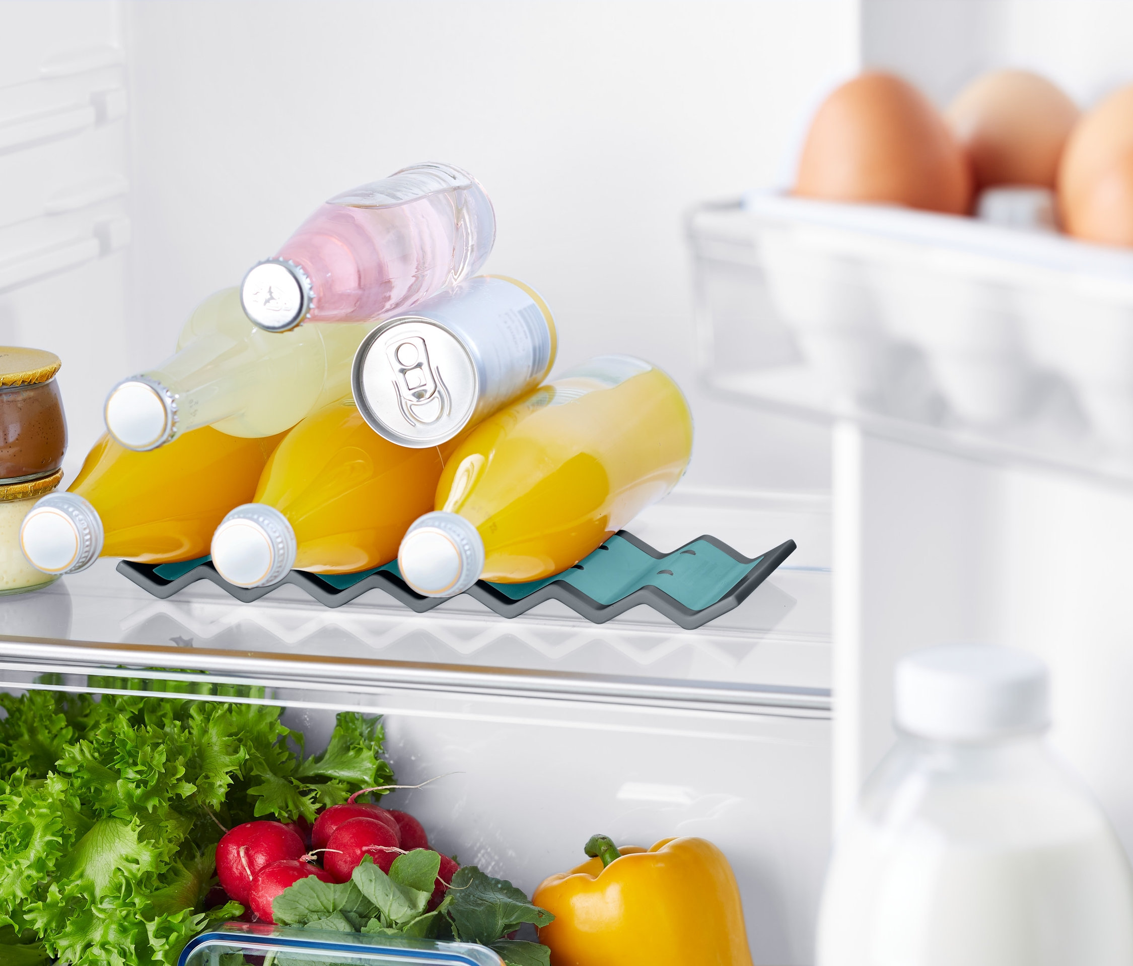 V lednici je drzak lahvi, v nemz jsou umisteny lahve s napoji. Dale jsou videt vejce, zelenina a dzemy.