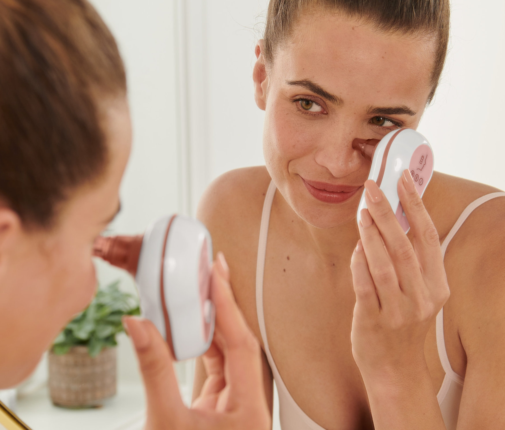 Žena používá čistič pórů na obličej před zrcadlem.