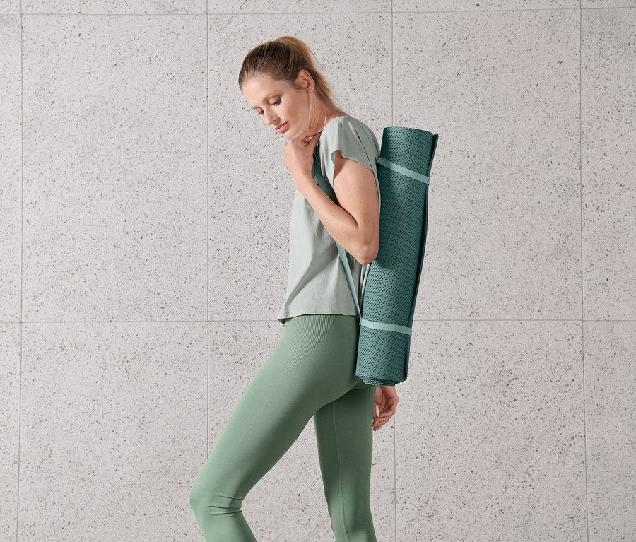 Žena nese podložku na jógu a cvičení.