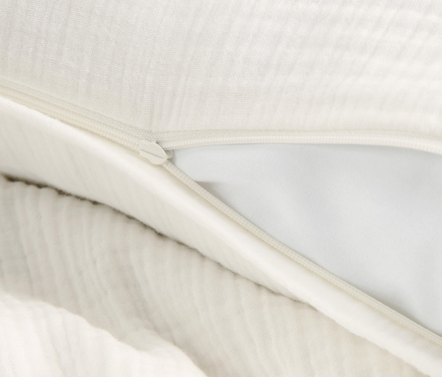 Detail mušelínového povlečení krémové barvy se zipem.